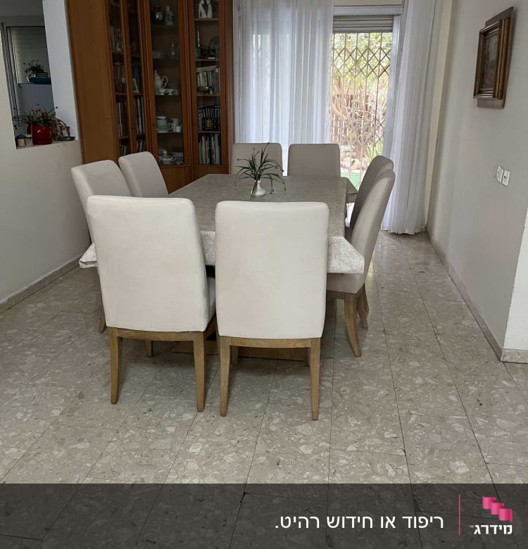 כיסאות מרופדים סביב שולחן אוכל בחדר אוכל מואר